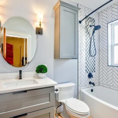 Elegant modern bathroom featuring chevron tiles, oval mirror, and sleek fixtures for a contemporary look.